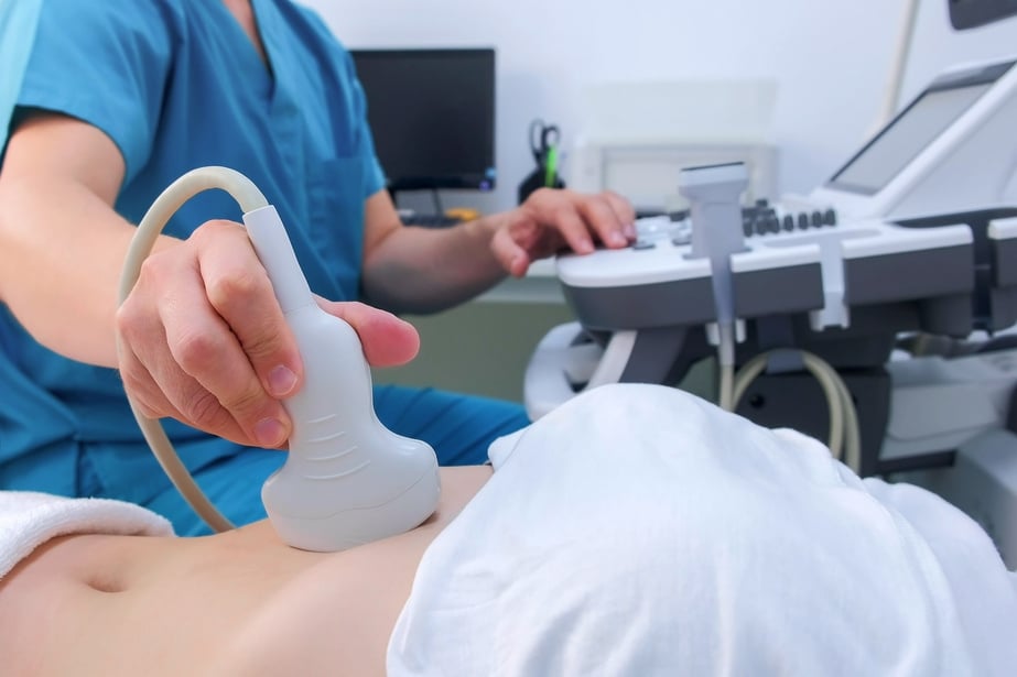 Man doctor making abdominal ultrasound to diagnostic stomach to woman in clinic.